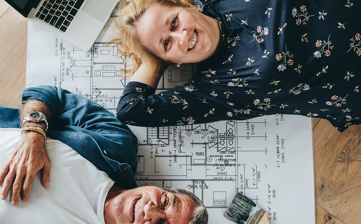 Couple smiling & laying over home plans
